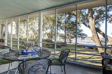 a patio with a view of mature trees and a lake